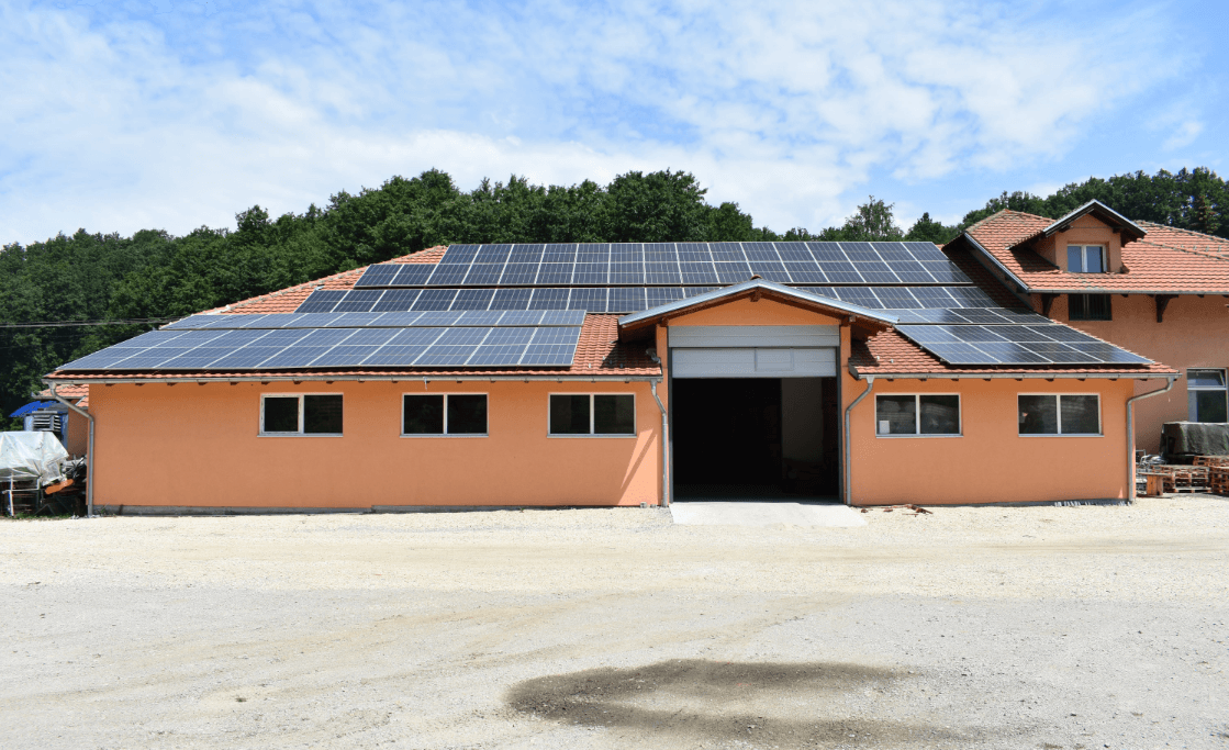 Solar panels on a peach-colored building's red tile roof with a large open garage.
